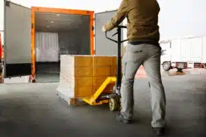 Someone using a pallet truck to load some stock into the back of a van.