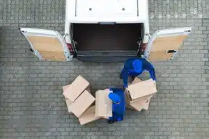Two delivery drivers unloading boxes from the back of a van.